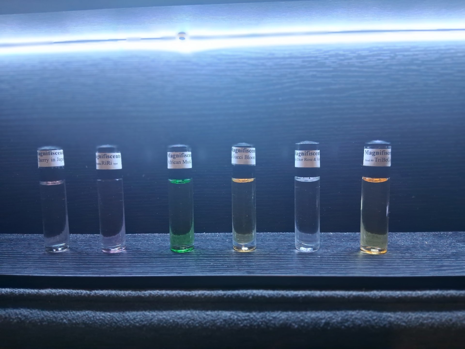 Row of Magnifiscents fragrance body oil roller bottles in assorted scents